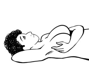 Person lying down with one arm under their head and the other hand examining their breast.